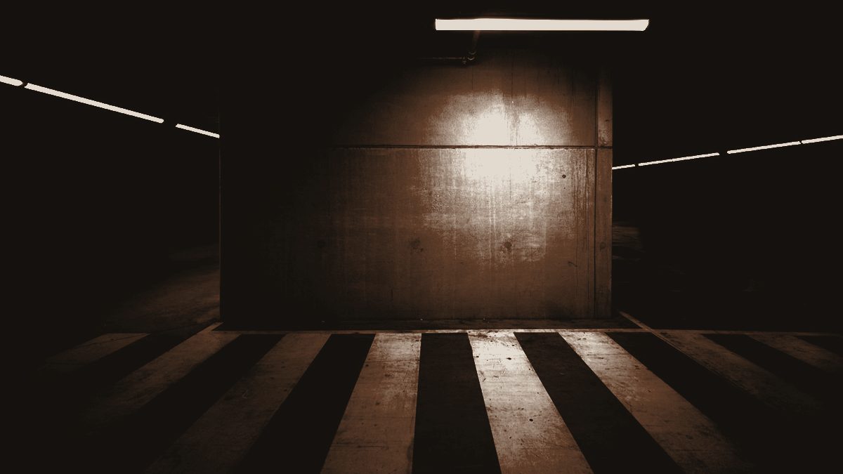 A quiet concrete room lit by a single overhead light
